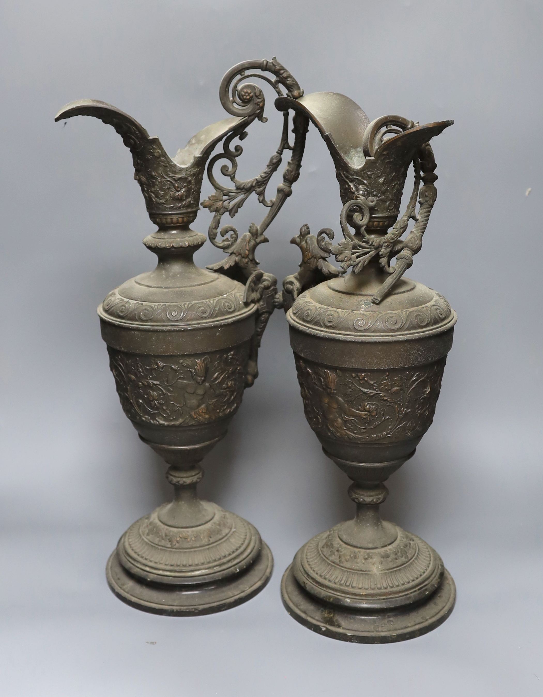 A pair of bronzed metal classical pedestal urns with scroll decoration and satyr masks (one handle detached), height 53cm